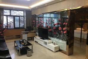 A modern living room with a flat-screen TV, a coffee table, and a decorative fish tank. - Wanhao Hotel (Hailun)