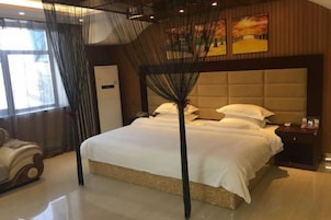 Quarto de hotel com cama grande, mesa de cabeceira, guarda-roupa e janela com cortinas.