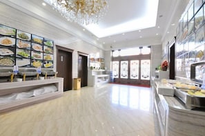 A spacious hotel lobby with a buffet area, a chandelier, and a large window providing natural light. - Wanhao Hotel (Hailun)