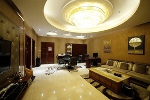 A spacious living room with a large flat-screen TV, a sofa, a coffee table, and a chandelier. - Wanhao Hotel (Hailun)