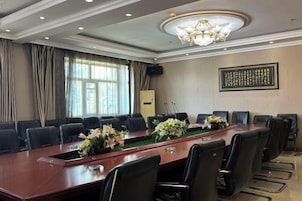 Un salón de conferencias con una larga mesa, varias sillas y un candelabro.