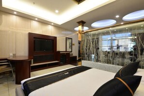 Ein Hotelzimmer mit Bett, Schreibtisch, Fernseher und Blick ins Freie.