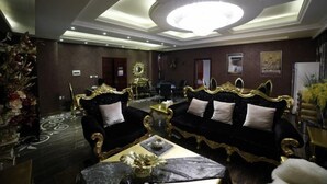 Um quarto luxuoso com mobiliário ornamentado em preto e dourado, um candelabro e um piso estampado.
