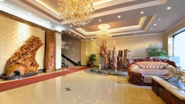 Um hall amplo com piso lustroso, um imponente candelabro e uma área de estar confortável.