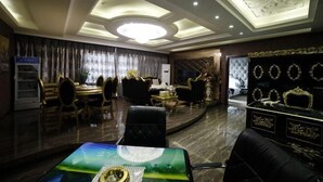 Um quarto amplo com uma mesa redonda, várias cadeiras, um sofá e um aparador decorativo.