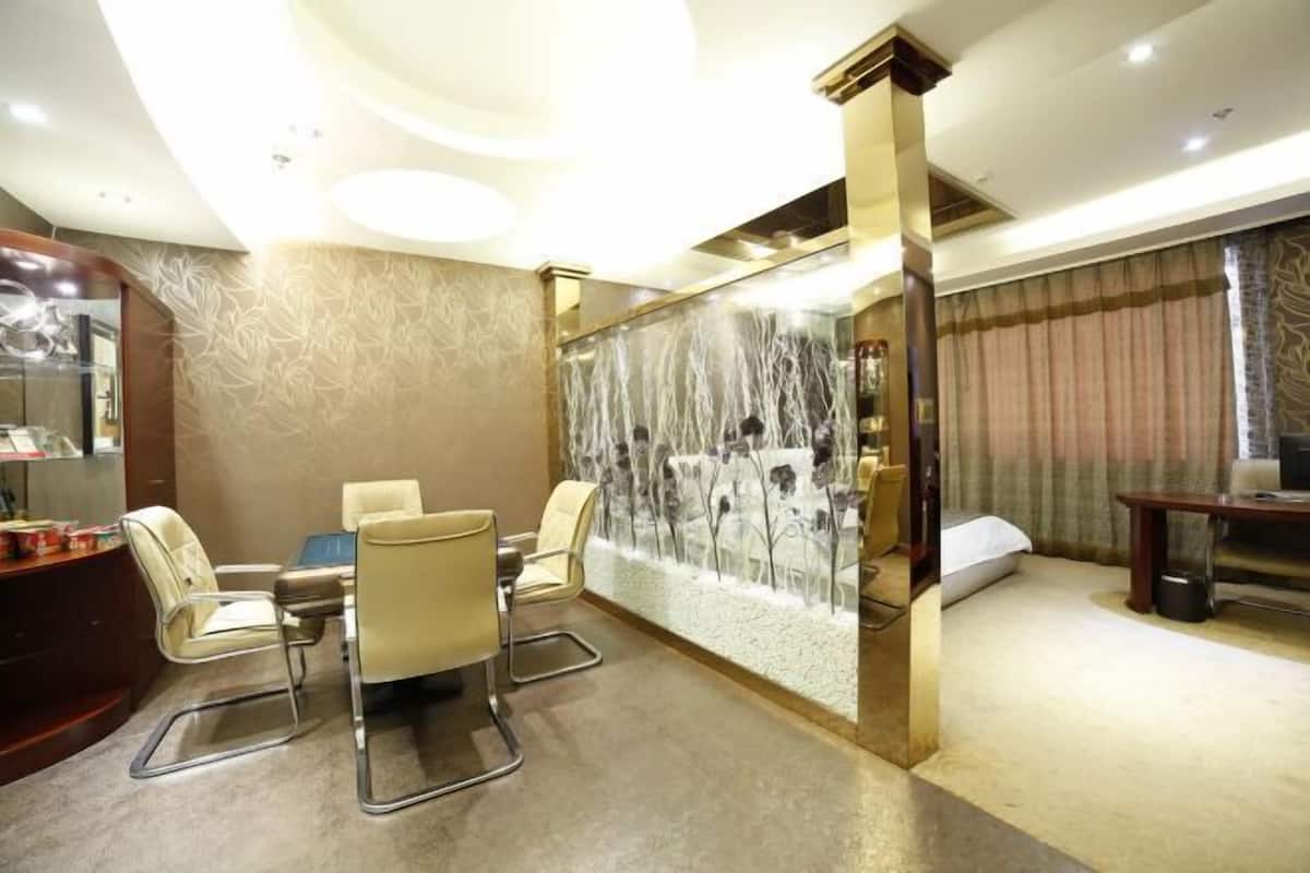 Una habitación de hotel moderna con comedor, un ventanal con cortinas y un panel decorativo en la pared.