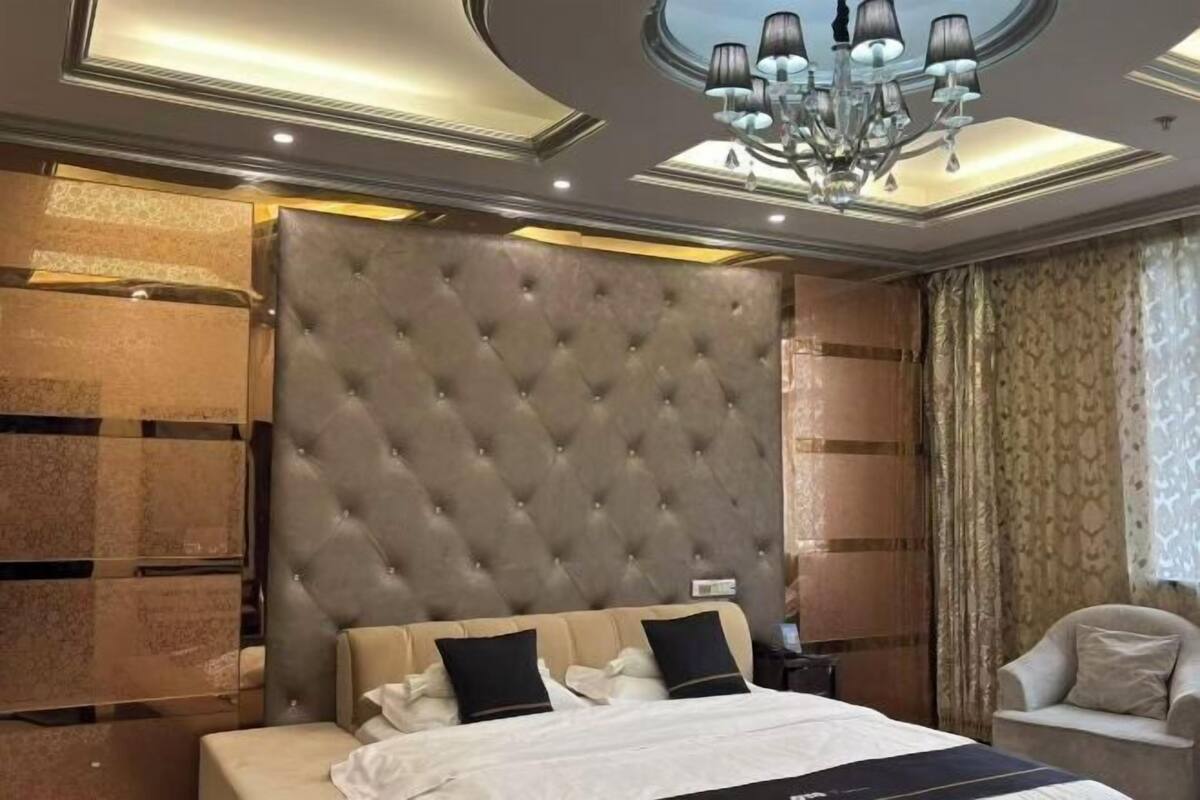 Un dormitorio con cabecera capitonada, cama con ropa de cama blanca, mesita de noche y una silla.