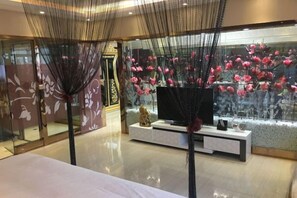 A hotel room with a bed, a television, a decorative wall, and a large window with flowers. - Wanhao Hotel (Hailun)