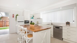 Una cocina moderna con armarios blancos, una isla de madera y un lavavajillas.