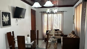 A modern living room with a dining area, a flat-screen TV, and a chandelier. - New Two bedroom apartment, totally equipped with a large covered Patio (Santiago De Los Caballeros)