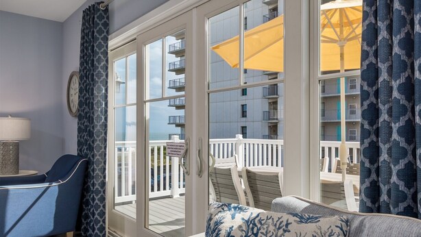 A balcony with a view of a building, a chair, a sofa, and a lamp.