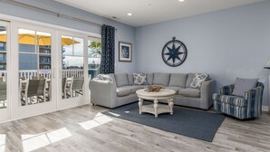 A spacious living room with a grey sofa, a round coffee table, and a patterned armchair.