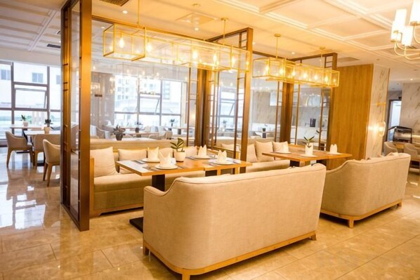A modern hotel lobby with seating areas, a reception desk, and large windows.