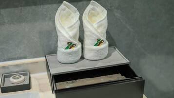 A pair of white slippers with a green and gold logo on a black box.