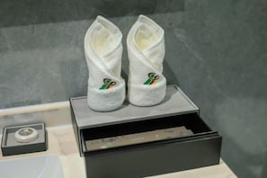 A pair of white slippers with a green and gold logo on a black box.