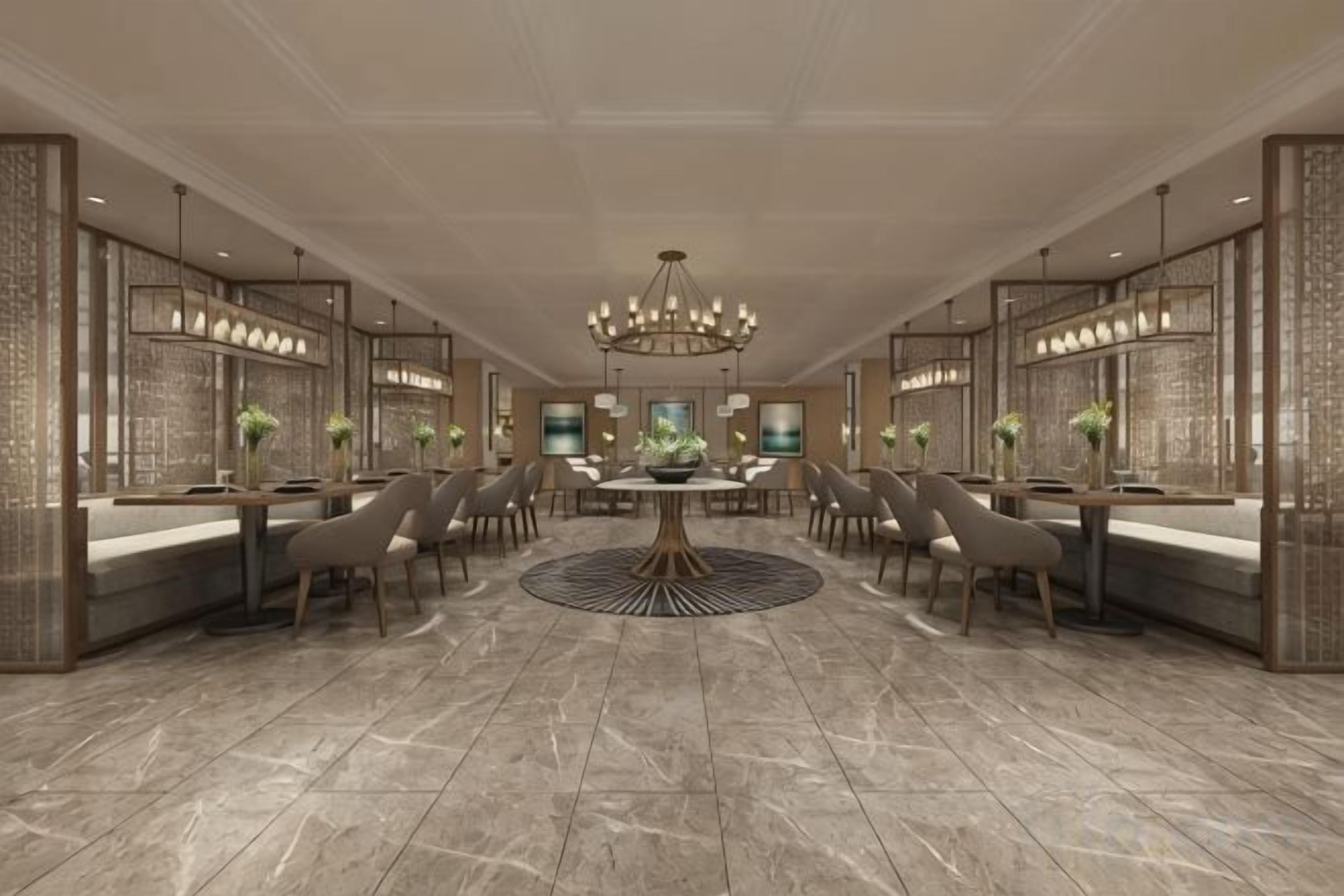 Un hall d’hôtel spacieux avec une table ronde, de nombreux espaces aménagés pour s’asseoir et un lustre.
