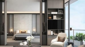 Ett modernt hotellrum med en säng, en sittgrupp med ett soffbord och en bokhylla.