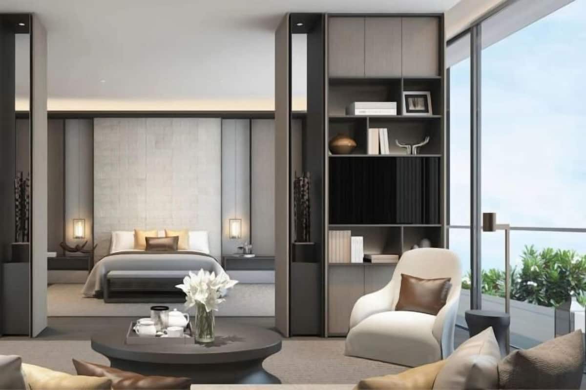 A modern hotel room with a bed, a seating area with a coffee table, and a bookshelf.