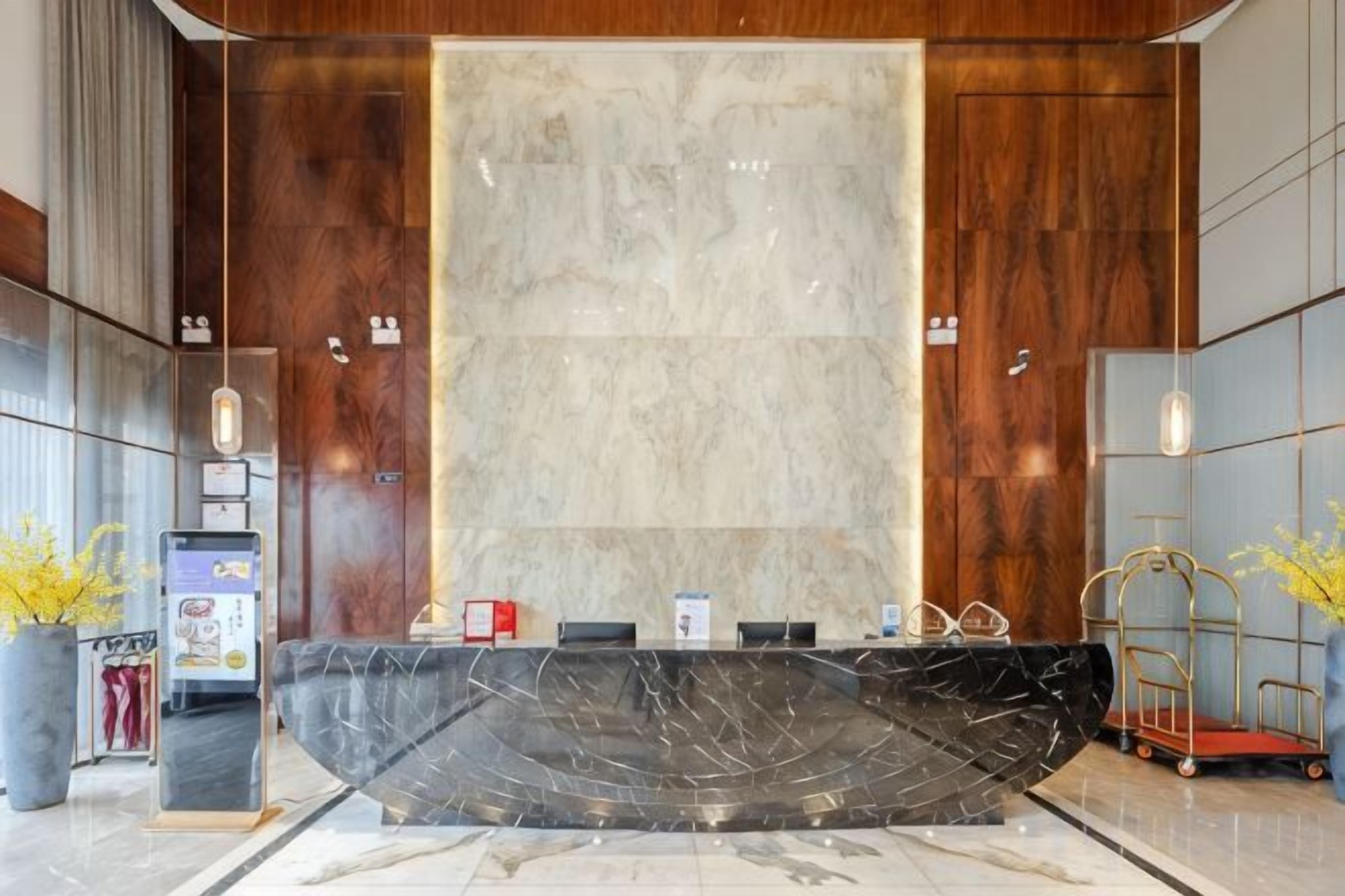 A reception desk with a marble top, wooden paneling, and a large mirror.