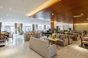 A spacious lobby with multiple seating areas, a reception desk, and large windows allowing natural light. - Yuhe Hotel (Jiajiang)