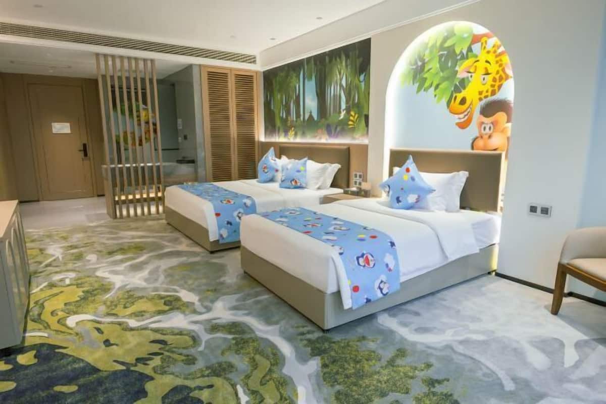 A hotel room with two beds, a large mural, and a patterned carpet.