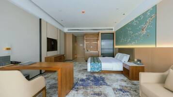 Una habitación de hotel moderna con una cama, un escritorio, una silla, un televisor y una obra de arte grande en la pared.