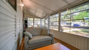 Un interior acogedor con sofá, mesa de madera y ventanas amplias que ofrecen vistas al exterior.