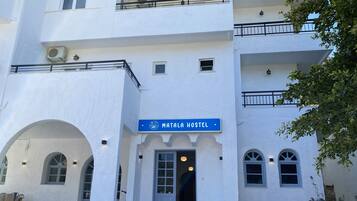 Ostello chiamato "Mata Hostel" con facciata bianca, diverse finestre e una insegna.