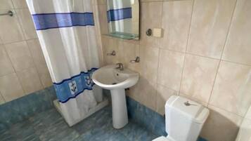 Baño con inodoro, lavamanos y cortina de ducha.