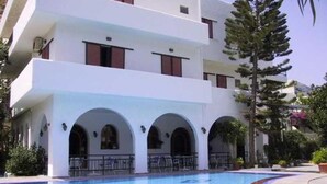 A modern building with a swimming pool, featuring multiple balconies and arched windows.