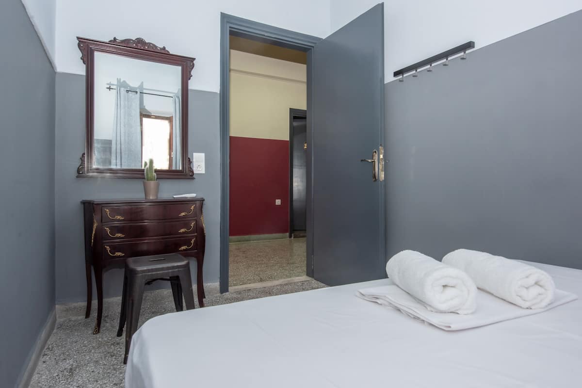 A hotel room with a bed, a dresser, a mirror, and a door leading to another room.