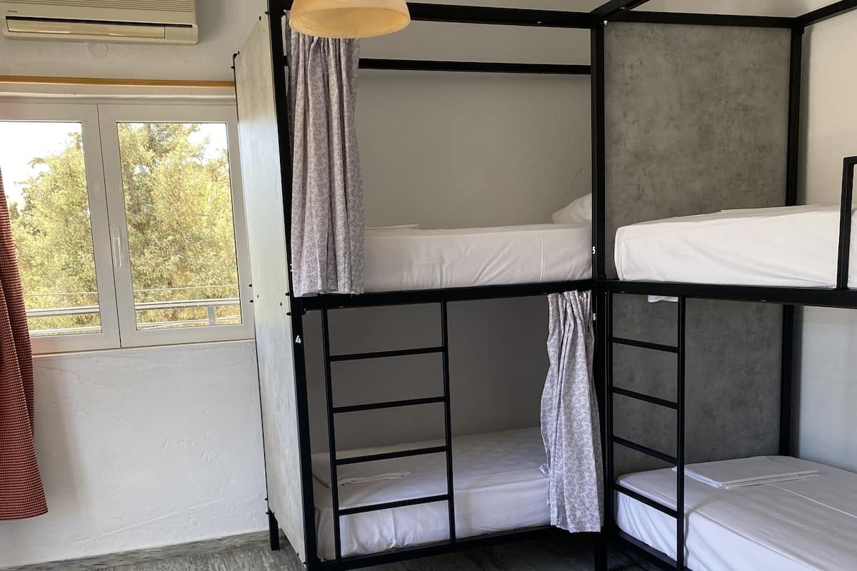 A bunk bed room with a window, curtains, and a hanging light fixture.