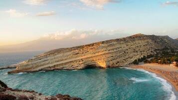 A coastal landscape with a cliff, beach, and ocean.