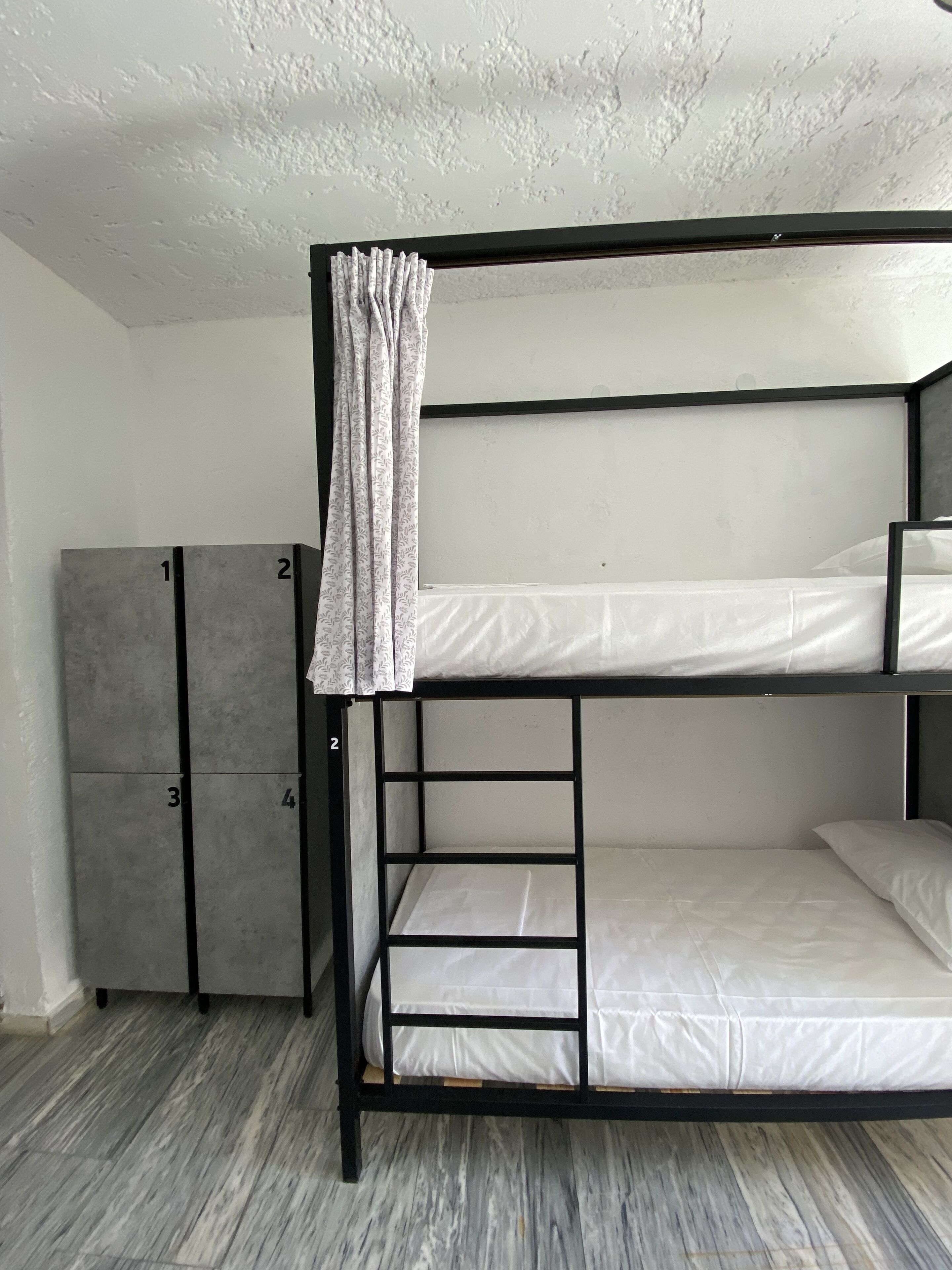A bunk bed with a wardrobe and a curtain.