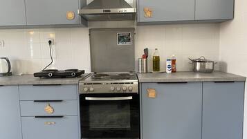 Una cocina con estufa, horno y varios utensilios sobre la encimera.
