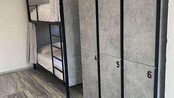 A bunk bed with a ladder, a hanging light fixture, and a wardrobe with numbered doors.