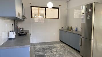 A modern kitchen with grey cabinets, a stainless steel refrigerator, and a marble-patterned floor.