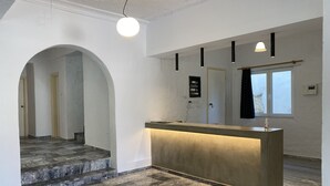 A hotel lobby with a reception desk, a staircase, and a window with a view.