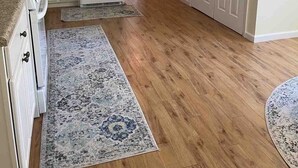 A kitchen with wooden flooring, white cabinets, and a refrigerator. There are two rugs on the floor. - Warwick Life - Leaf Peeping, Apple Picking, Skiing, Wineries, Breweries,Legoland (Warwick)