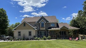 A two-story house with a stone facade, a large front porch, and a well-maintained lawn. - Warwick Life - Leaf Peeping, Apple Picking, Skiing, Wineries, Breweries,Legoland (Warwick)