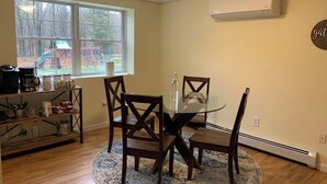 A dining area with a round glass table, dark wooden chairs, and a rug. There is a window with a view of a playground outside. - Warwick Life - Leaf Peeping, Apple Picking, Skiing, Wineries, Breweries,Legoland (Warwick)