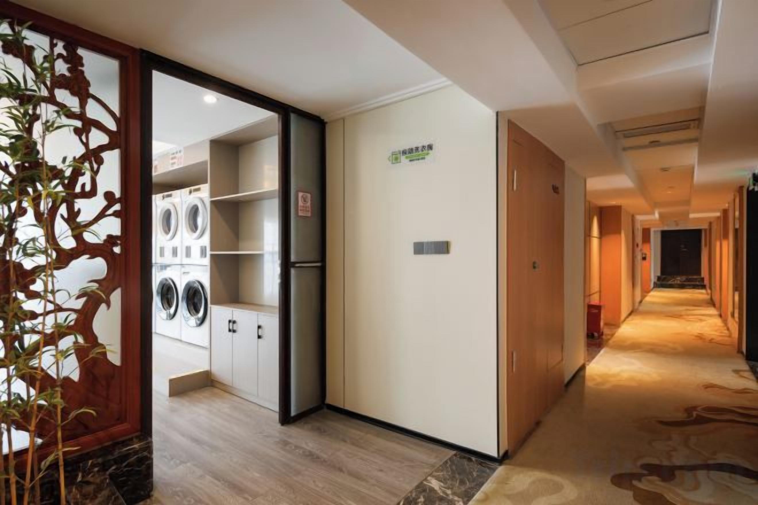 A hotel corridor with a laundry room, a reception area, and a carpeted floor.