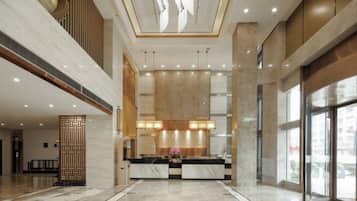 A spacious lobby with a reception desk, large windows, and a high ceiling.