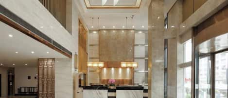 A spacious lobby with a reception desk, large windows, and a high ceiling.