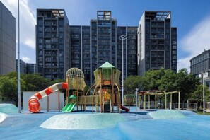 A playground with slides and climbing structures, surrounded by tall buildings. - Jia Yue Hotel (Tongxiang)