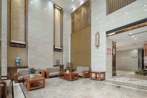 Un vestíbulo con disposición de asientos, una recepción y una gran pared con paneles verticales.