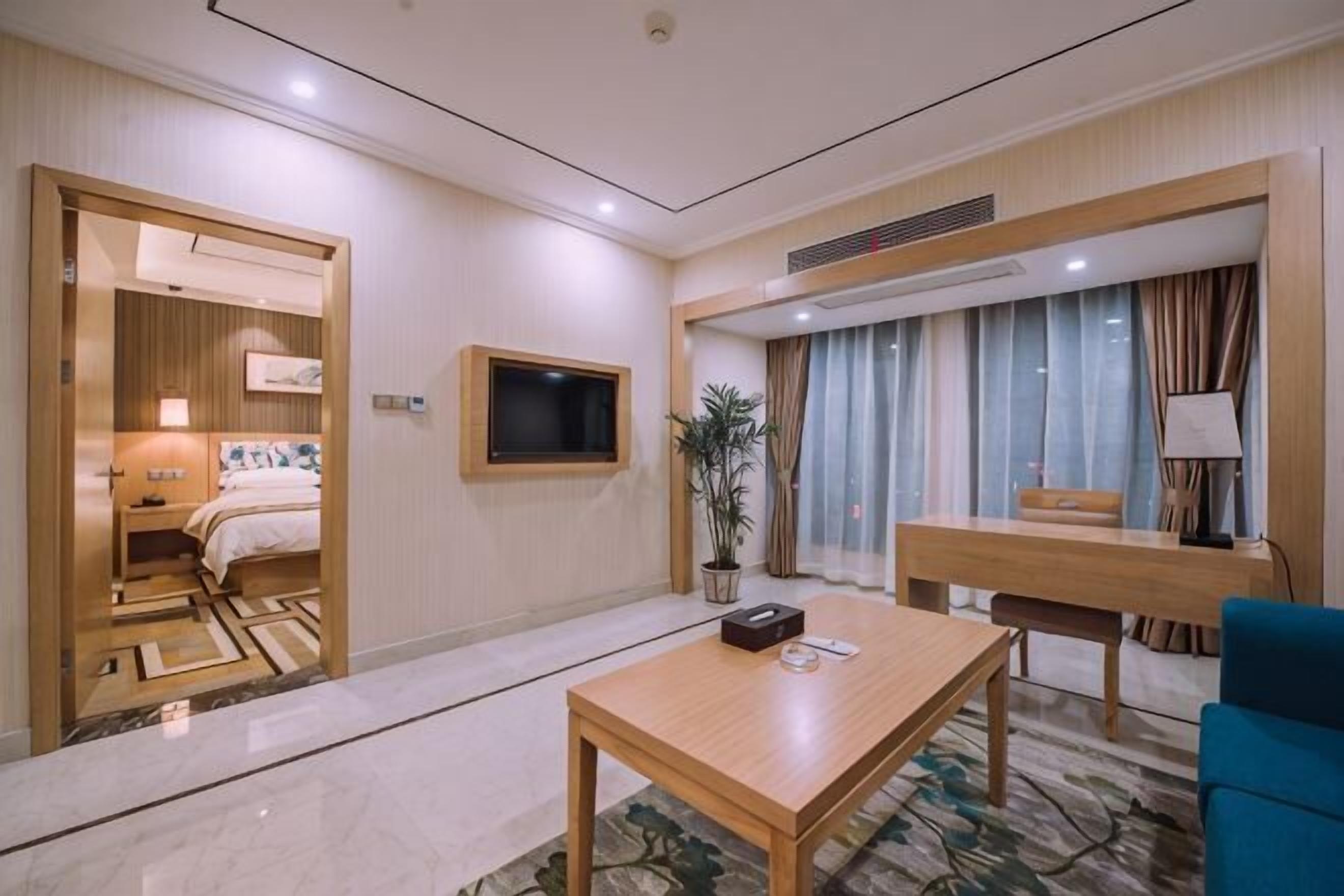 A hotel room with a bed, a TV, a dining table, and a seating area.