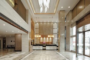 A spacious lobby with a reception desk, large windows, and a high ceiling. - Jia Yue Hotel (Tongxiang)
