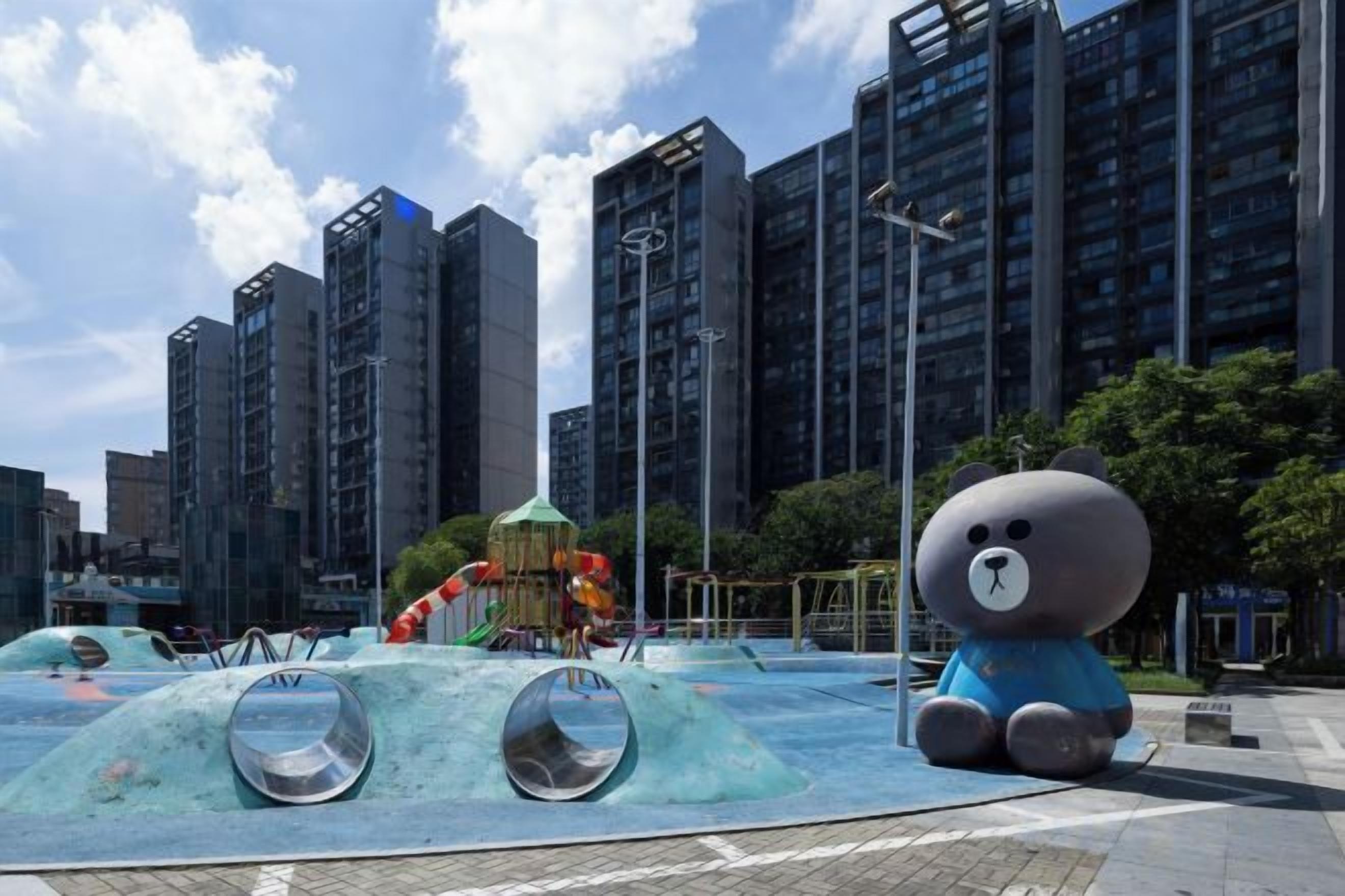 Un parque infantil con una gran escultura de oso y una zona de juegos acuáticos.