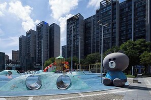A playground with a large bear sculpture and a water play area.